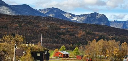 Photo of a diverse landscape including rural settlement, forest-clad slopes and mountains in the back